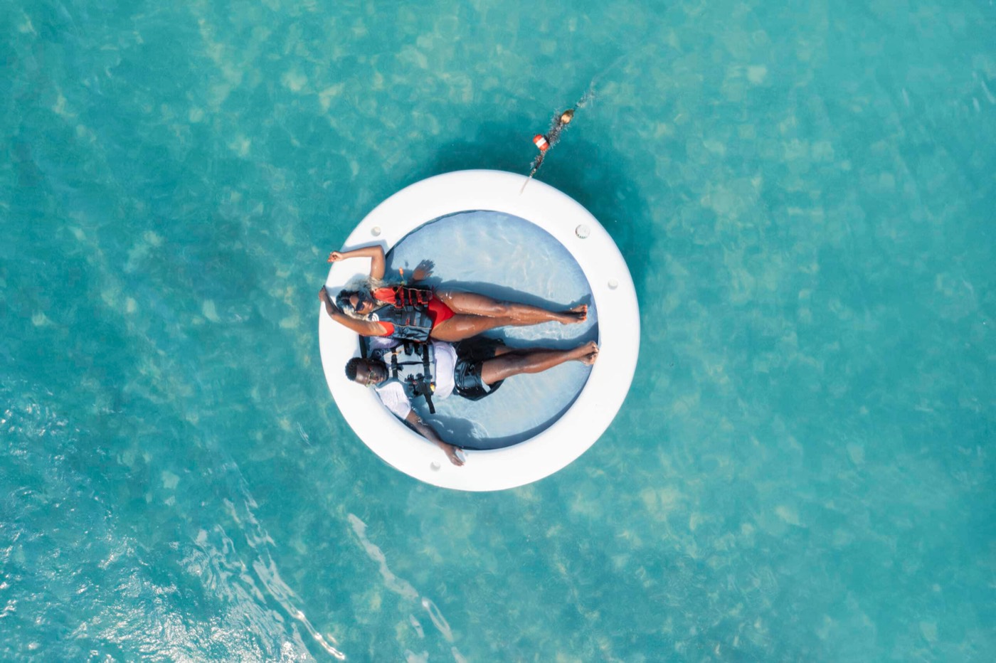 A guest floating on a water hammock in clear turquoise water