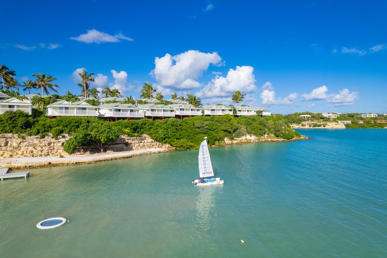 A sailboat gliding past the waterfront cottages